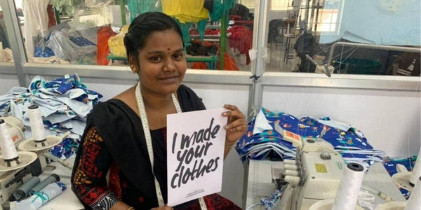 Image of a lady from Shine Organic Clothing Company making Ducky Zebra clothes and holding a sign saying 'I made your clothes'