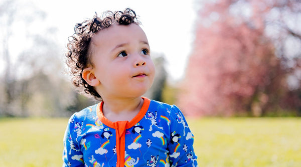 Toddler wearing Ducky Zebra zip-up sleepsuit outside in the summer