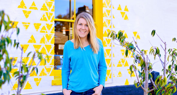 Sally Dear, CEO of Ducky Zebra, standing in front of a white wall with a yellow window