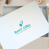 White Ducky Zebra Gift Box with Turquoise Foil Branding, stating 'Ducky Zebra. Playful Designs, Thoughtfully Made'
