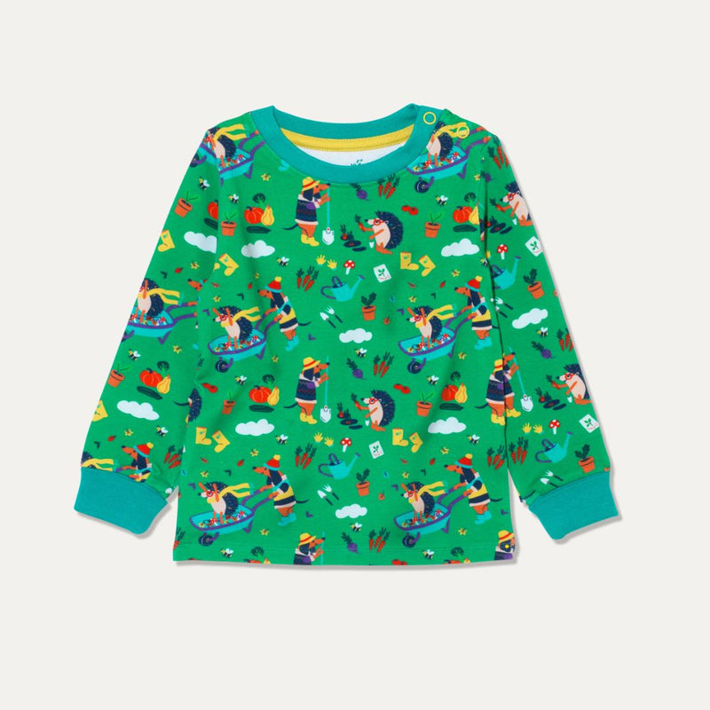 Image of Ducky Zebra green top with repeat print of a dog and hedgehog gardening together and playing with a wheelbarrow. The print includes pictures of pumpkins, carrots and squash. The top has a turquoise trim and yellow poppers on one shoulder for easy dressing.