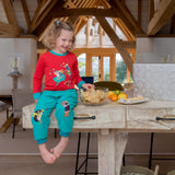 A girl sitting on the kitchen surface, eating crisps and wearing Ducky Zebra cord trousers and a Ducky Zebra red top. She's smiling at the camera.