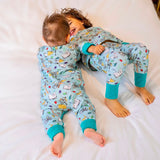 Baby and toddler playing on the bed, wearing Ducky Zebra x Roald Dahl PJs and Sleepsuit