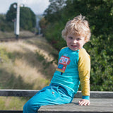 Child wearing a Ducky Zebra fire engine sweatshirt with teal trousers.