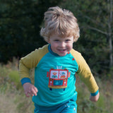 Child running towards the camera, wearing a Ducky Zebra sweatshirt with a fire engine on it.