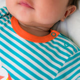 Image of a baby wearing a long sleeve turquoise stripe bodysuit with flame orange trim and roll-up arm cuffs. The image focuses on the neckline of the bodysuit, including two turquoise poppers on the side of the neck for easy opening.