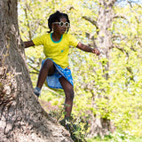 Image of a child, climbing a tree, wearing a Ducky Zebra skort, with the underneath shorts showing and a Ducky Zebra yellow t-shirt