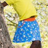 Image of a child leaning against a tree wearing a Ducky Zebra yellow t-shirt and colourful, kite flying repeat print skort with pockets