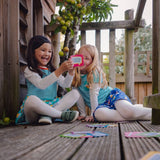 Image of two happy children sitting in a tree house, wearing Ducky Zebra clothes, playing with the Conversation Cards