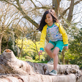 Image of a girl climbing on a fallen tree, wearing a Ducky Zebra jumper and turquoise shorts 