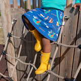 Image of a child on a climbing frame wearing a colourful ducky Zebra skirt with a repeat print pattern of a fox, cheetah, duck and crocodile playing musical instruments. The child is wearing bright yellow wellies.