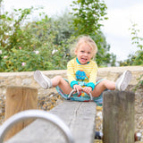 Image of a happy girl on a seesaw wearing a Ducky Zebra yellow top and green skort