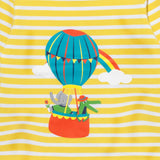 Close up image of a print on a Ducky Zebra yellow and white stripe t-shirt. The print is of a crocodile and elephant enjoying a hot air balloon ride together, with a rainbow in the background.