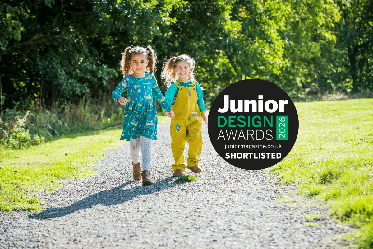 Two children walking towards the camera wearing Ducky Zebra unisex 'Highland Pals' clothes and the badge 'Junior Design Awards' on top