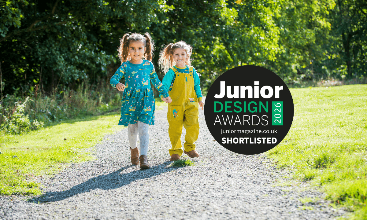 Two children walking towards the camera wearing Ducky Zebra unisex 'Highland Pals' clothes and the badge 'Junior Design Awards' on top