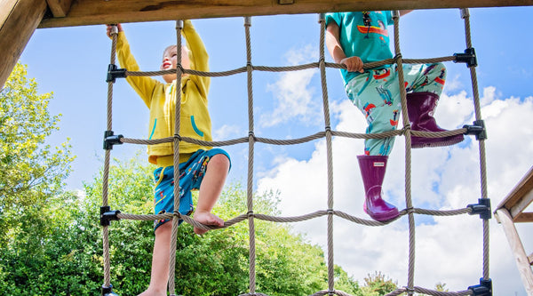 Two children climbing in the park, wearing colourful, unisex Ducky Zebra clothes 