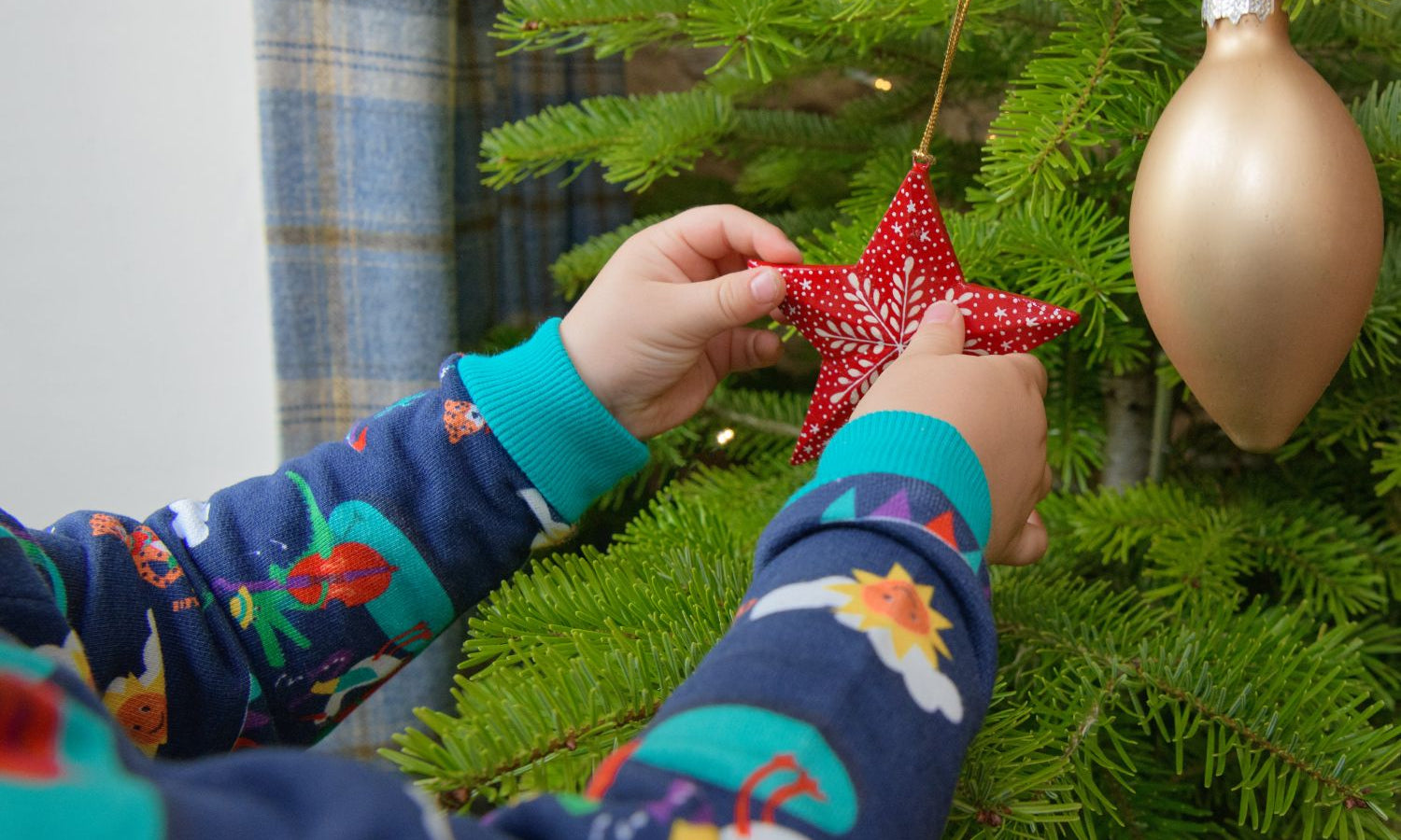 Child wearing Ducky Zebra jumper while decorating a Christmas Tree