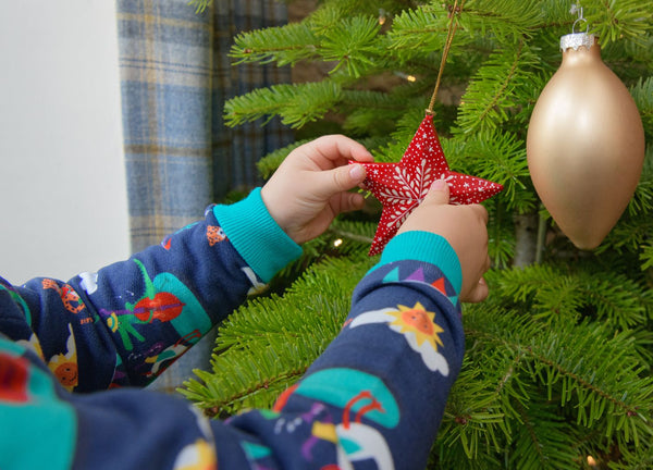 Child wearing Ducky Zebra jumper while decorating a Christmas Tree