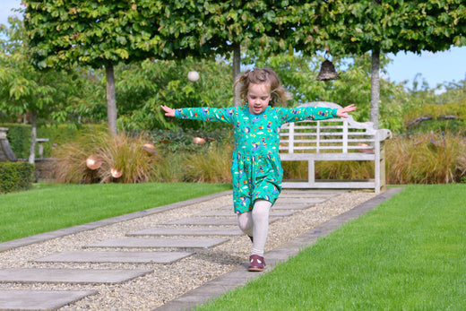 Girl wearing an organic cotton green dress with pockets by Ducky Zebra