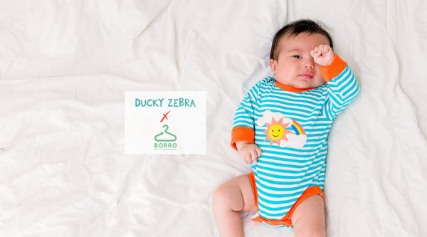 Image of a tired baby lying on a white blanket with the Borro rental logo by its side