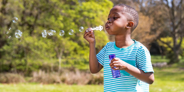 Image of happy boy outside blowing bubbles in a Ducky Zebra turquoise t-shirt