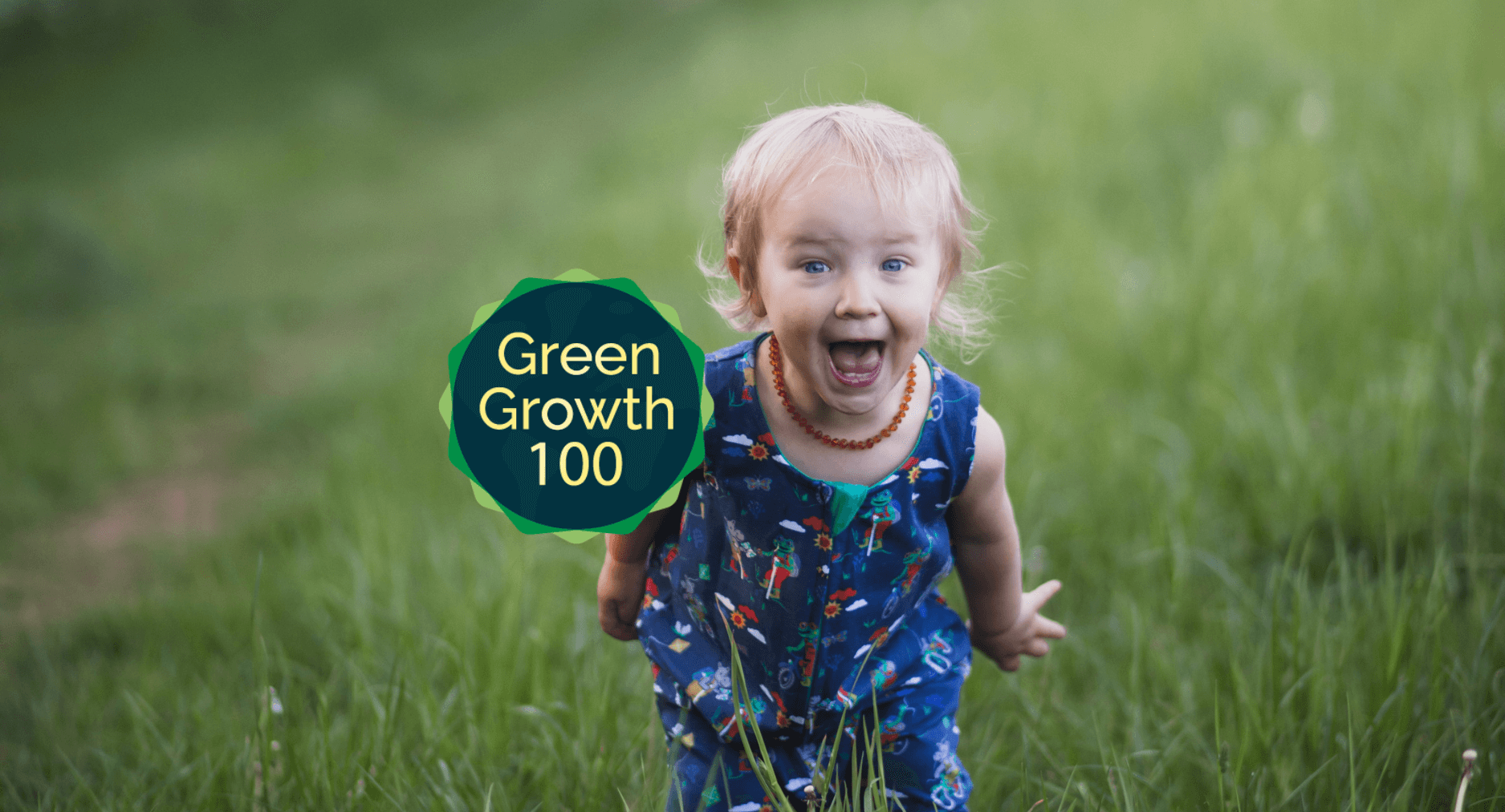 Happy Child in grass wearing Ducky Zebra romper, with the logo 'Green Growth 100' overlaid