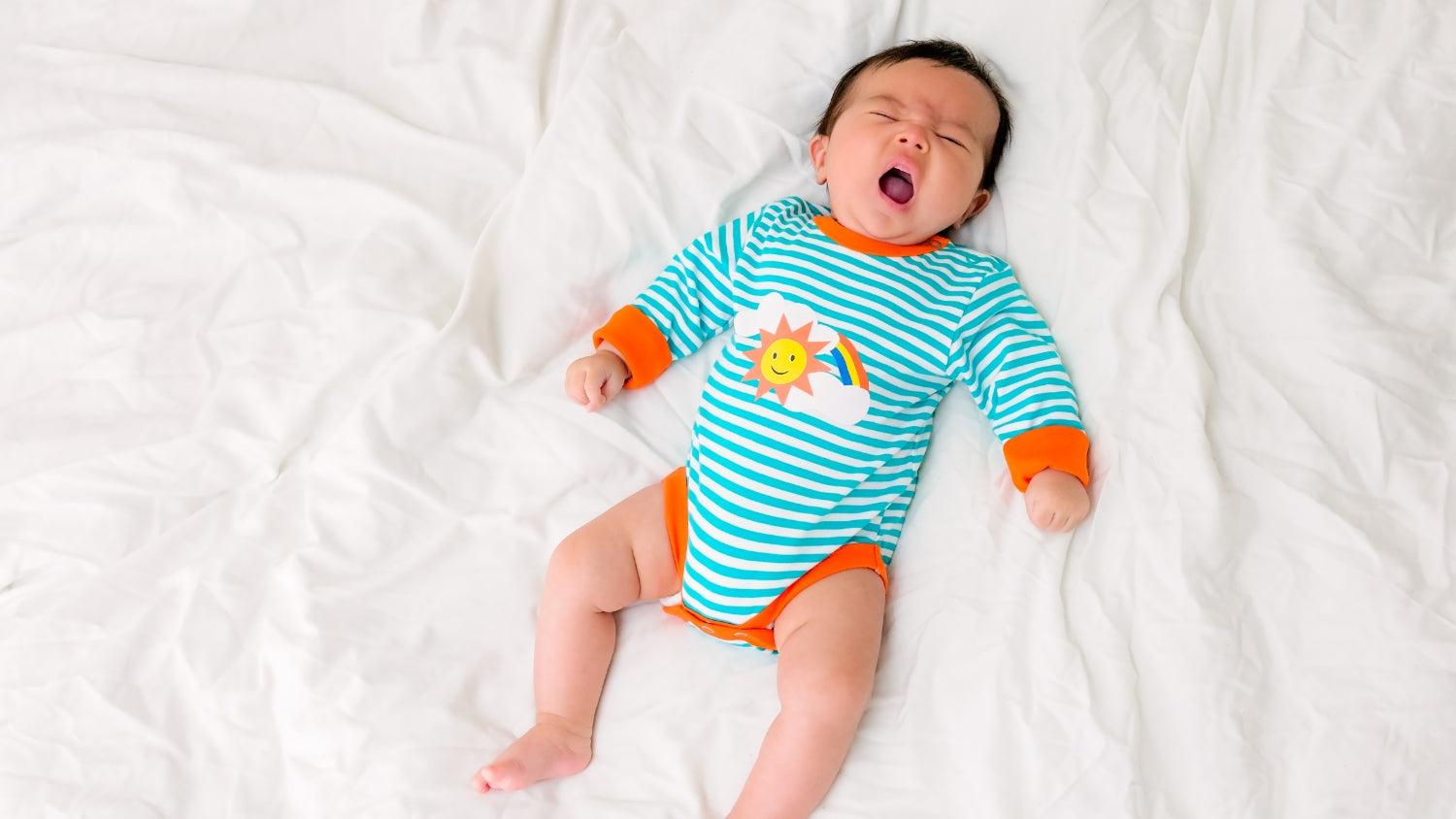 Sleepy baby wearing Ducky Zebra unisex bodysuit with rainbow and sun print