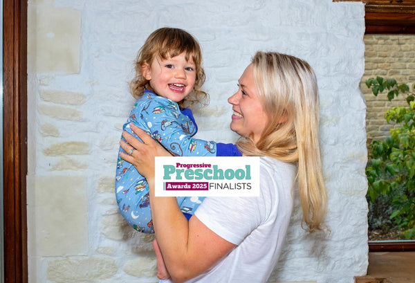 Smiling mum holding up a smiling toddler, who's wearing A Ducky Zebra x Roald Dahl Sleepsuit. The photo has the logo 'Progressive Preschool Awards 2025 Finalists'