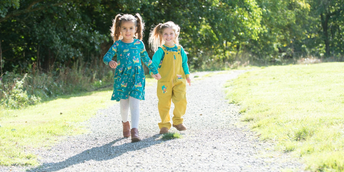 Two smiling children wearing Ducky Zebra yellow cords and green dress