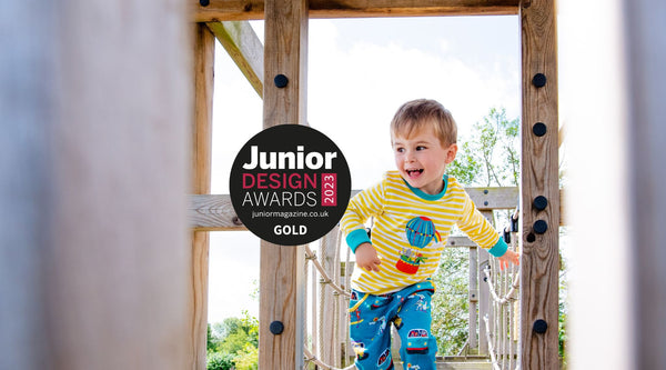 Image of a smiling boy wearing Ducky Zebra unisex kids clothes with the Junior Design Awards Gold Logo