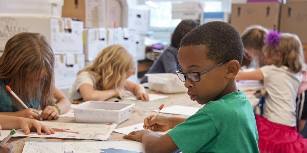 Image of primary school children in a classroom with the Lifting Limits Logo on top