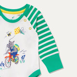 Close up of baby Organic Cotton bodysuit with a picture of a cycling, kite flying hippo and a bee. The baby bodysuit has a green and white stripe arm, green cuffs and poppers on the neck.