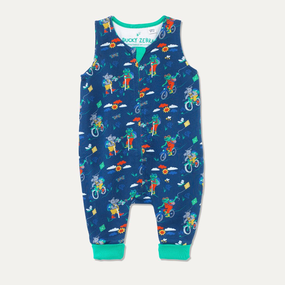Blue organic cotton dungarees with a zip down the front and a repeat print of a cycling and walking frog and hippo. The dungarees have a green roll-down cuff.