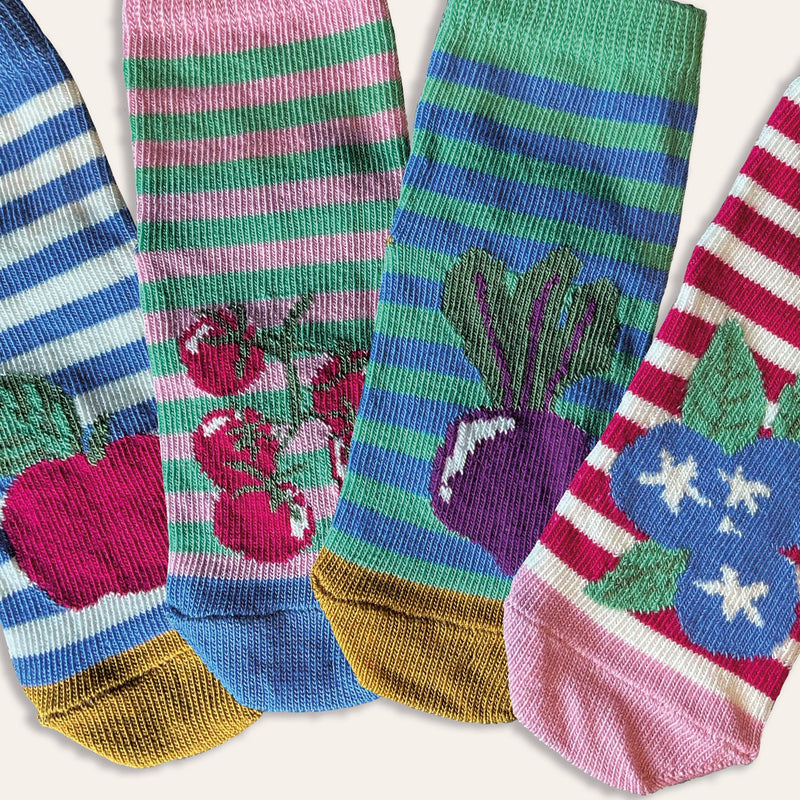 Close up of 4 baby socks with fruits on each including apples, blueberries, beetroot and tomatoes. The socks are striped, with a pop of colour