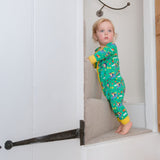 Image of a toddler climbing up the stairs wearing a green Ducky Zebra footless romper with a fun hedgehog and dog print.