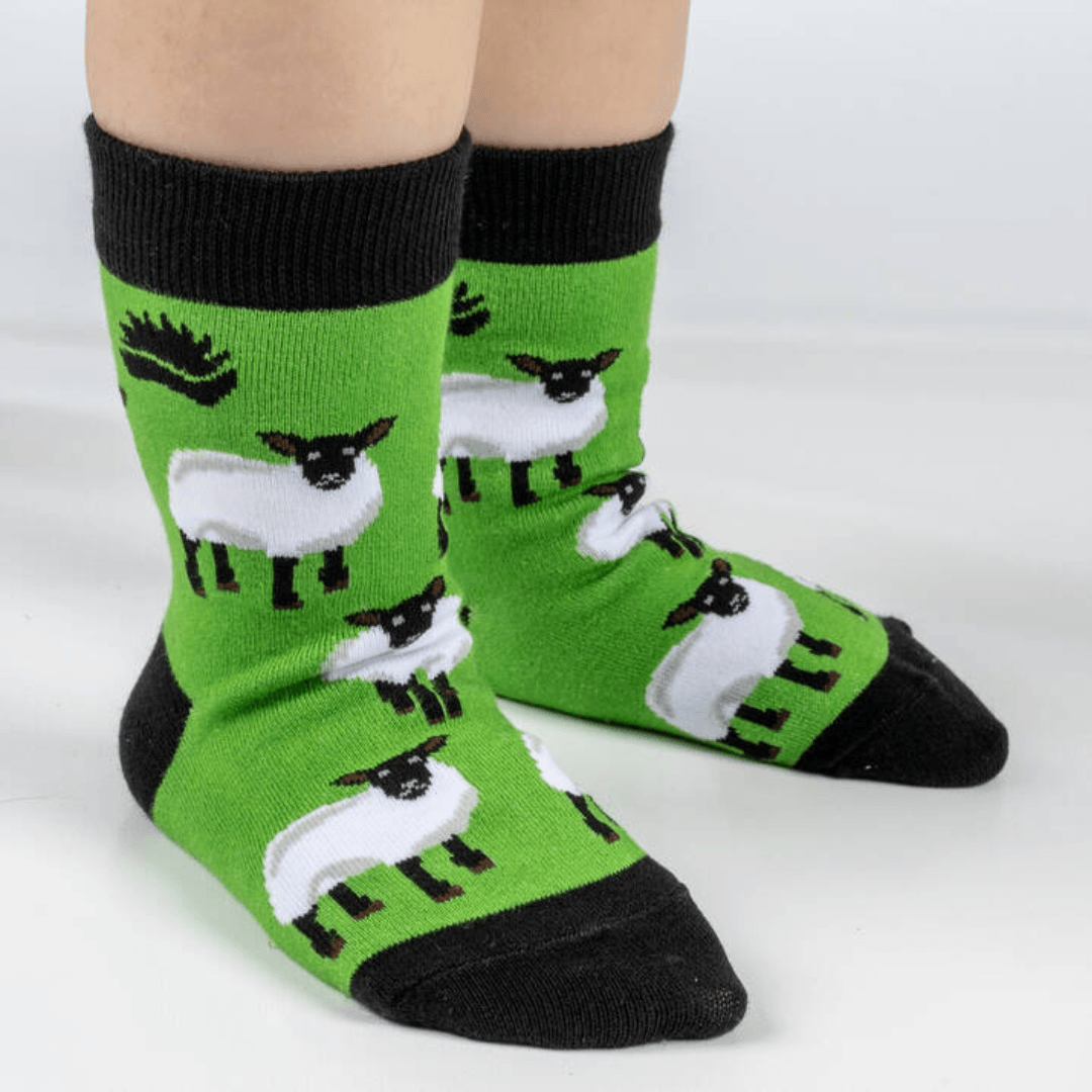 Child wearing green socks with repeat sheep pattern