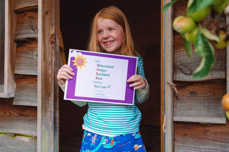 Image of a happy girl holding a Ducky Zebra affirmation certificate 