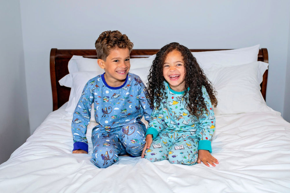 Children wearing Ducky Zebra's Organic Cotton Roald Dahl Pyjamas, sitting on a bed