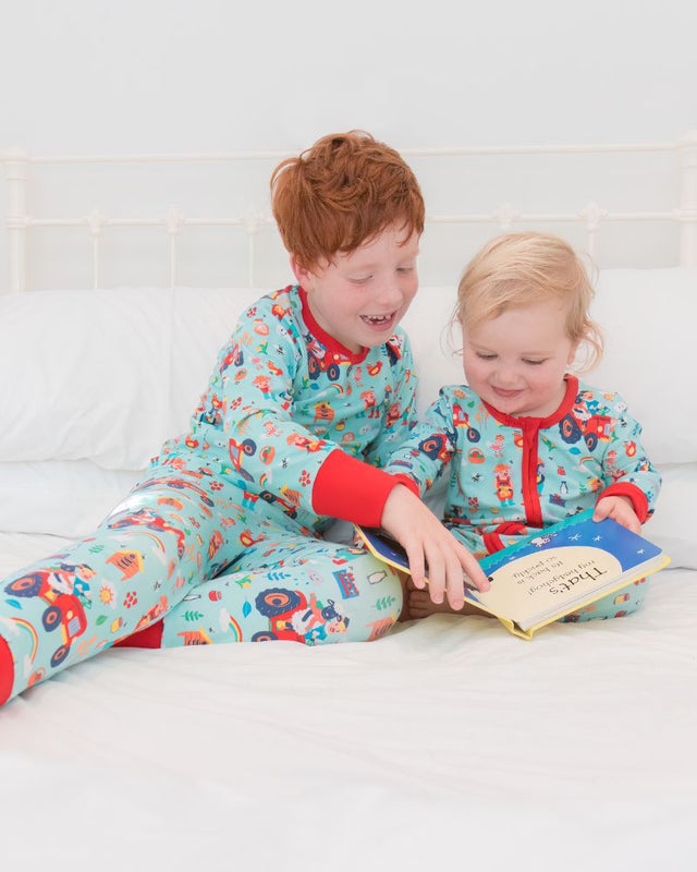 Two smiling children in bed wearing colourful, unisex Ducky Zebra pyjamas