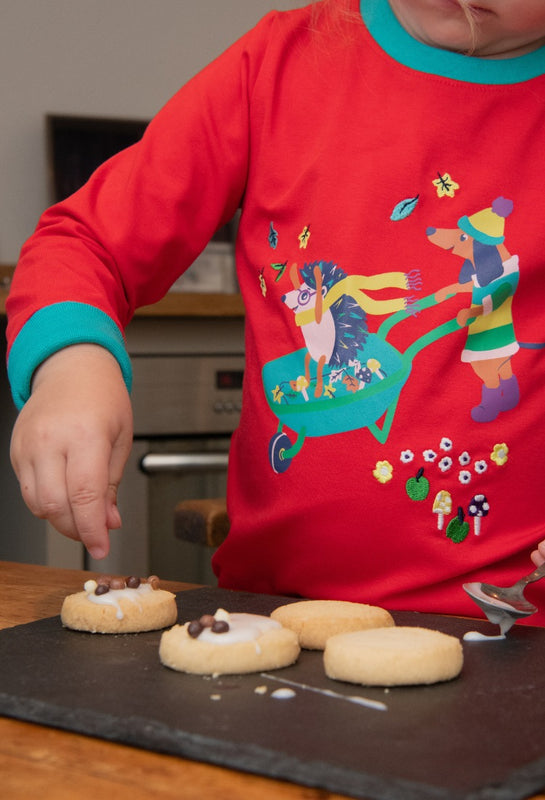 Image of child wearing a red unisex top with a fun hedgehog and dog print