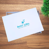 White A4 Ducky Zebra Gift Box with Turquoise Foil Branding, stating 'Ducky Zebra. Playful Designs, Thoughtfully Made'. The box is resting on a table.