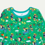 Close up of green kids' skater dress with fun repeat print of a dog and hedgehog playing in a wheelbarrow and gardening. The print includes bees, pumpkins, carrots and wellies. The dress a turquoise neck trim and contrasting yellow buttons on the shoulders. 