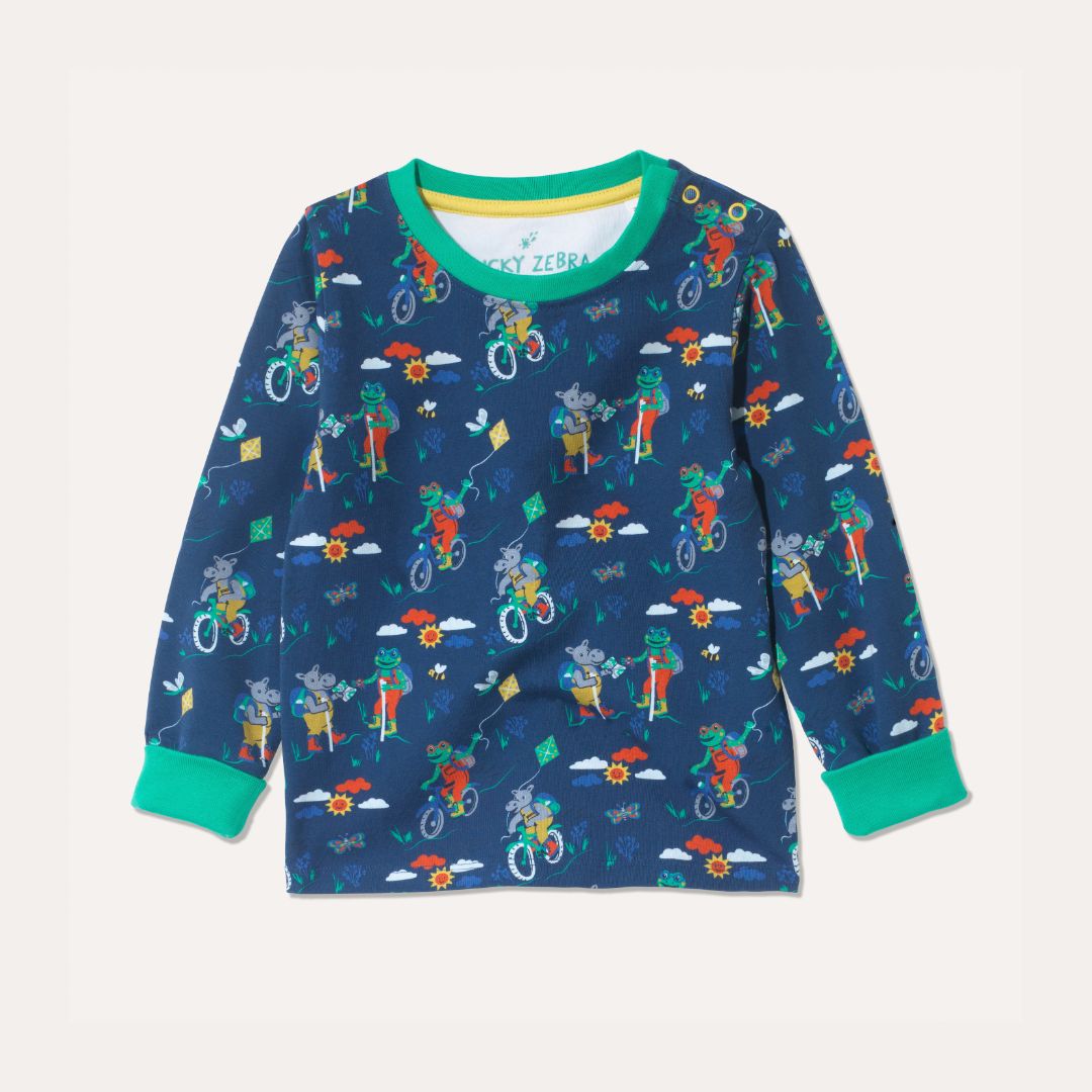 Blue organic cotton long sleeve top with repeat print of a frog and hippo on bikes and walking. The top has roll-up green cuffs and yellow poppers on the right hand side of the neck.