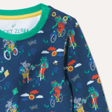 Close up of blue organic cotton long sleeve top with repeat print of a frog and hippo on bikes and walking. The photo focuses on the yellow poppers on the right hand side of the neck.