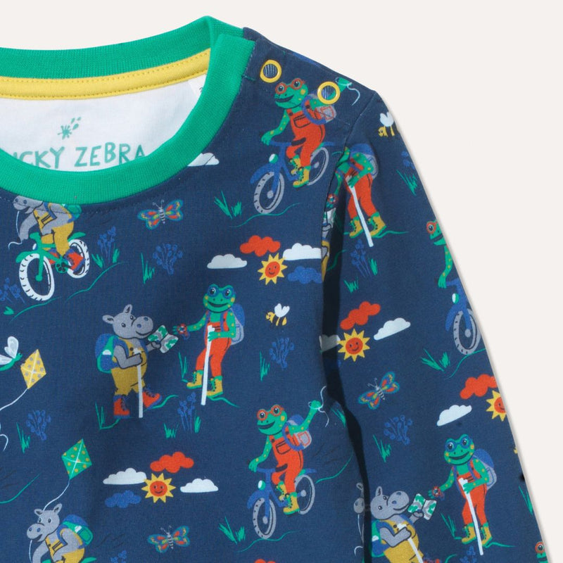 Close up of blue organic cotton long sleeve top with repeat print of a frog and hippo on bikes and walking. The photo focuses on the yellow poppers on the right hand side of the neck.