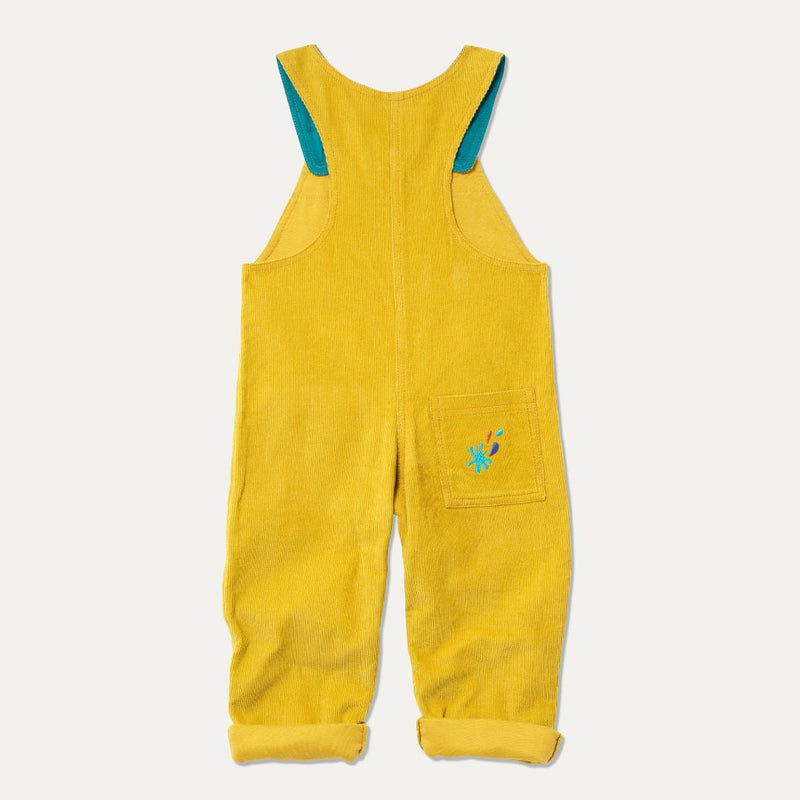 The back of a pair of yellow cord kid dungarees, rolled up with an unfixed cuff and an embroidered splash on the back pocket