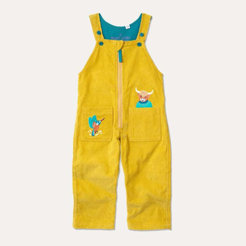 Mustard yellow kids cord dungarees with front zip and two big pockets - each with an appliqué. One is a highland cow, the other a king fisher.