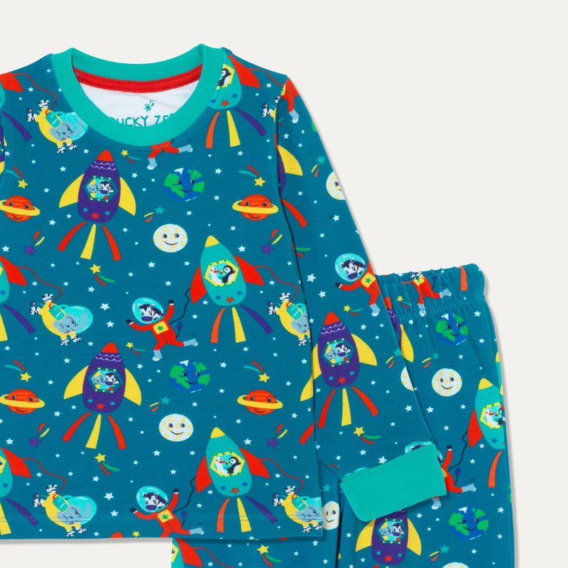 Close up image of kids' unisex pyjamas with a fun space themed print, showing an elephant, zebra, puffin and duck exploring space, surrounded by planets and shooting stars. The pyjamas have a teal background and turquoise cuffs.