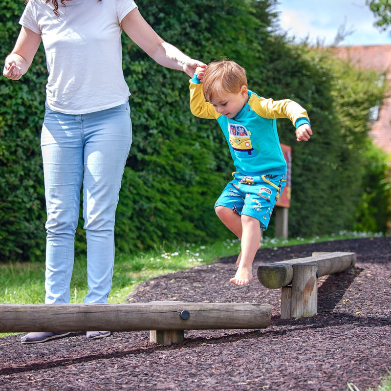 Young boy playing in the park with his mum, wearing Ducky Zebra shorts and a Ducky Zebra jumper with campervan appliqué