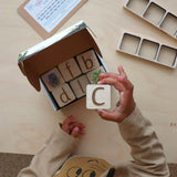Child holding up a The Phive Phonics Tile with the sound 'C' on it